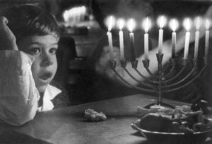 Photo of young child and lit menorah.