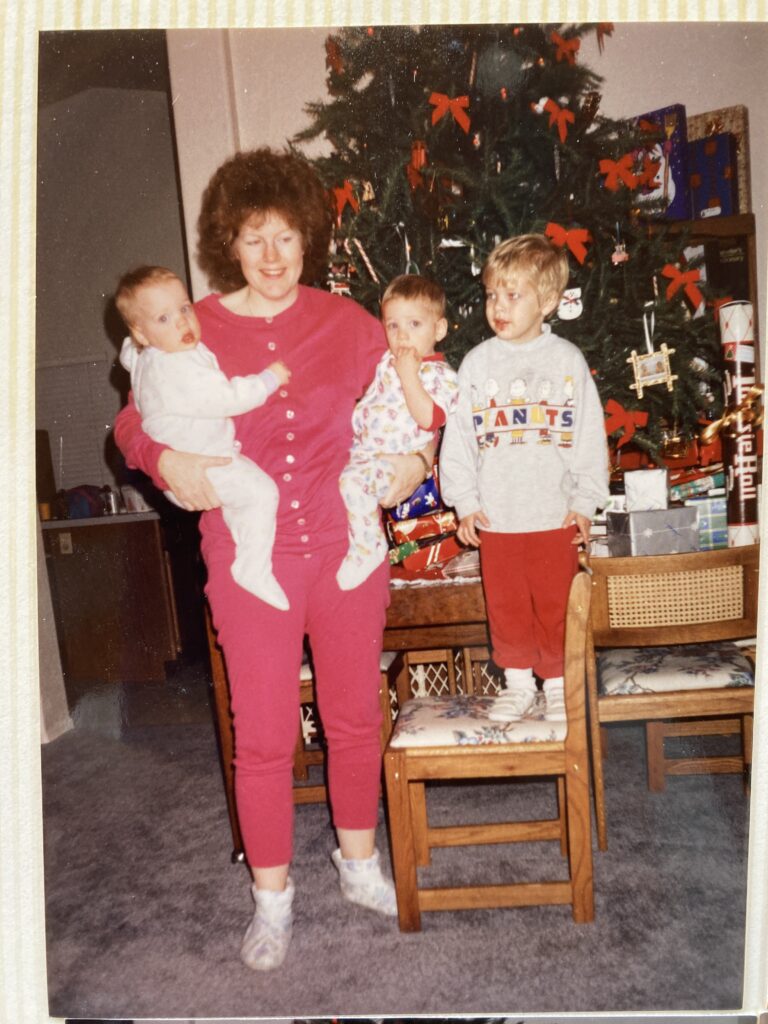 Mom holding twins, with toddler, at Christmas
