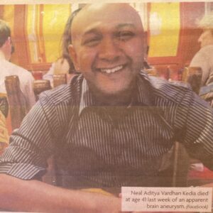 Newspaper photo of Neal Aditya Vardhan Kedia, Phoenix dry cleaner. He smiles at the camera from across the table.